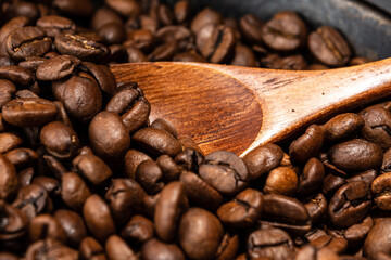 Freshly roasted coffee beans in a cast iron skillet. Linen napkin. A natural stone. Dark background.
