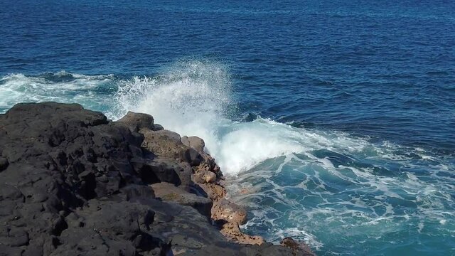 HD Hawaii Kauai slow motion static of ocean waves crashing up out of upper right frame against lava rock in lower left quadrant