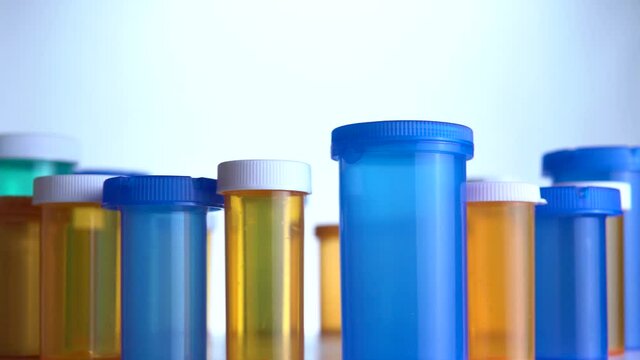 Extreme macro view of pharmaceutical generic prescription drugs and pills bottles on the pharmacy table top. Slow smooth sliding. Pharma companies developing potential coronavirus antiviral concept.