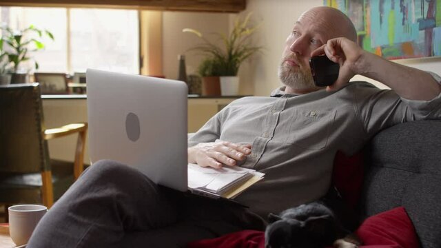 Man with a stack of bills piling up gets bored and antsy while waiting on hold