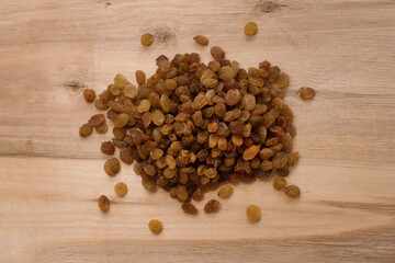 light brown raisins lies in bulk on a wooden background