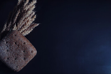 Fresh loaves of bread with wheat and gluten on a black table. Bakery and grocery concept. Fresh, healthy sorts of rye and white loaves food closeup. Fresh homemade bread with cereals.