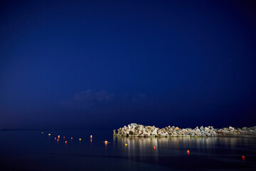 Fototapeta na wymiar Black Sea at night with stars and fly lanterns in the water