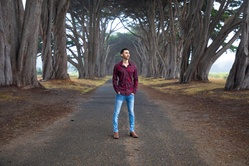Fototapeta premium Male model dressed up standing in a tree tunnel road