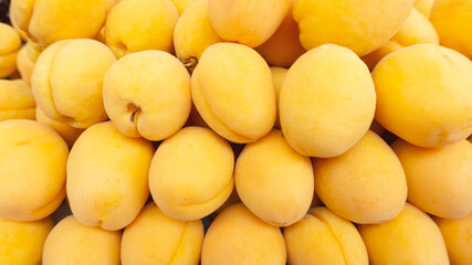Fototapeta na wymiar Yellow apricots close-up. Apricot fruit background with copy space. Juicy ripe apricots at the supermarket counter in the summer.