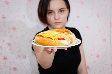 A beautiful girl holds a plate of delicious hot dogs in front of her.