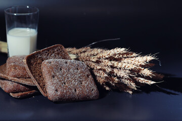 Fresh loaves of bread with wheat and gluten on a black table. Bakery and grocery concept. Fresh,...