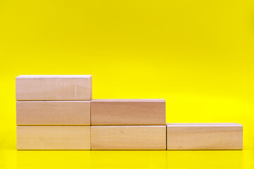 Stacking wooden blocks for in shape of staircase on yellow background with a copy of the space. Business development, strategy concept. Building success foundation