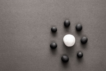 Small black plasticine balls surrounding a larger white one. Concepts of oppression and racism,...