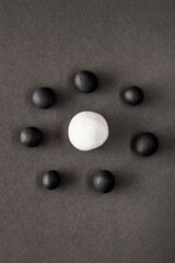 Small black plasticine balls surrounding a larger white one. Concepts of oppression and racism, diversity and violence in these modern troubled times
