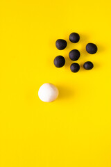 One big white ball and many black smaller plasticine balls in a group. Concepts of race and racism....