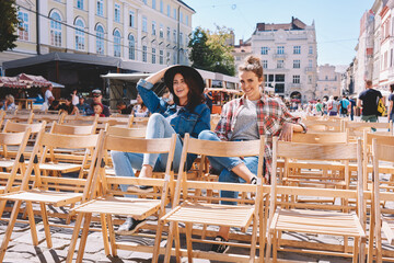 Cheerful female friends spending vacations in old city Lvov after sightseeing. Two good looking women enjoying sunny spring day while having free time together and loudly laughing