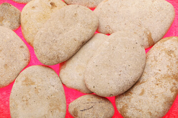 Gray smooth sea stones from the shore against the background of water drops. Backlight below. Background color is red.
