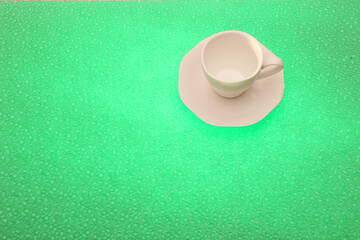 White cup for coffee with a saucer on a bright green background. The background is highlighted below.