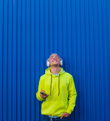 one young man or teenager millennial listening music with his phone and headphones looking up...