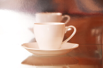 White cup with coffee on a glass table. Background - mirror 3D reflection.