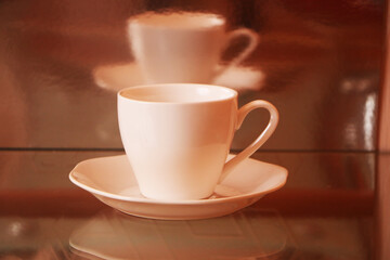 White cup with coffee on a glass table. Background - mirror 3D reflection.
