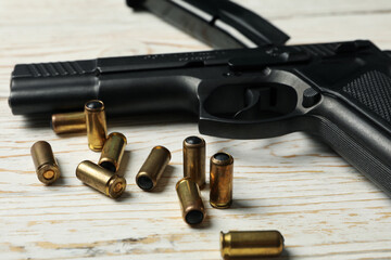 Pistol, bullets and magazine on wooden background