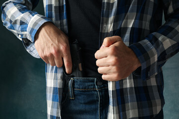 Man takes out a gun from jeans, close up. Robber