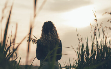 
A girl stands with her back and looks at the sea, a girl at sunset near the sea