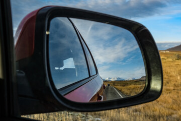 reflection in the rearview mirror. landscape with a road, mountains, field and car. Iceland. road trip individual travel