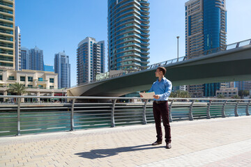 A male advertising agent chooses a building to install outdoor advertising in the city Business man with a plan diagram in his hands in the city center.