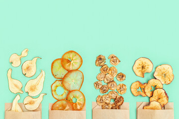 Dry slice fruits apple, banana, persimmon, pear. Tasty dehydrated fruit chips for plant-based diet. Trendy food for vegetarian. Bright colors flat lay with copy space.