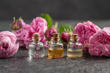 Three bottles of essential oil with cabbage rose flowers