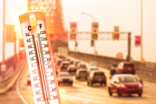 Thermometer in front of cars and traffic during heatwave in Montreal.