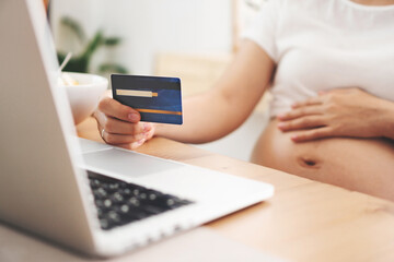 Pregnant Woman making online shopping on laptop at home