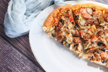 Slice of cheese pizza on a plate on wooden table.