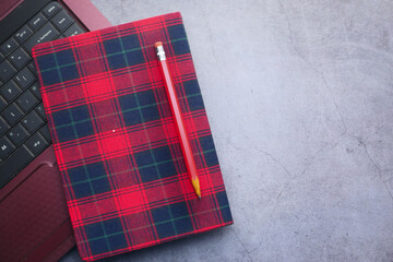 Red color notepad, pencils and laptop on black background 