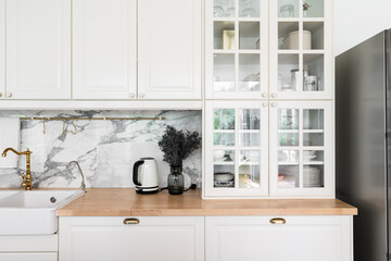 Modern classic kitchen interior with kitchen appliances and white ceramic sink with gold mirror...
