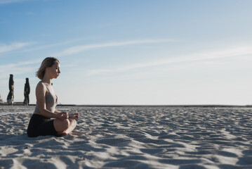 unity with nature. Young beautiful woman sits on the sand and meditates. Camping fresh air and breeze.