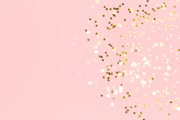 Gold stars confetti scattered on a pink pastel background. Festive concept with copy space.