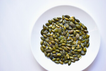 Fried delicious peeled pumpkin seeds on a white plate
