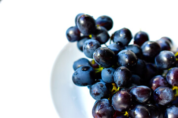 Black and delicious grapes on a white plate
