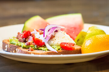 Breakfast for a healthy lifestyle. Avocado toast, poached egg and sliced fruit.