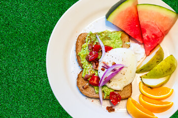 Breakfast for a healthy lifestyle. Avocado toast, poached egg and sliced fruit.