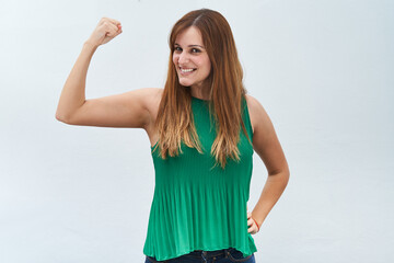 Happy young woman making the gesture of strength isolated on a white background.