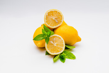 Group of fresh and yellow lemons with a sprig of mint isolated on white background