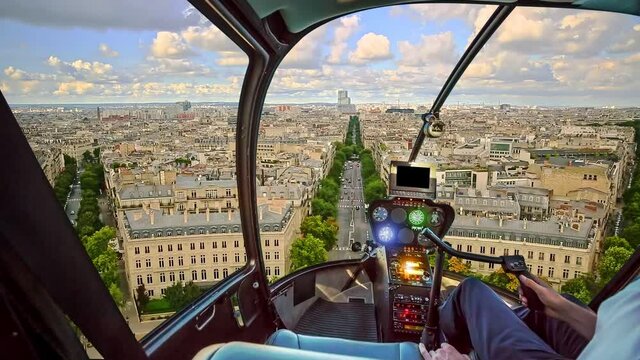 Helicopter cockpit flying on Paris skyline at sunset light. Scenic flight above Place de l'Etoile and Avenue de Wagram road of Paris skyline at sunset.