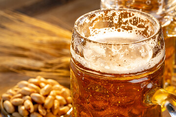Draft beer in glasses and peanut on wooden surface