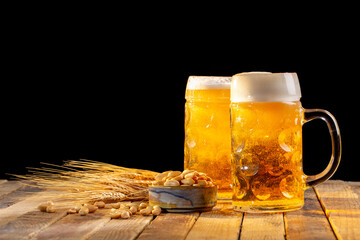 Draft beer in glasses and peanut on wooden surface