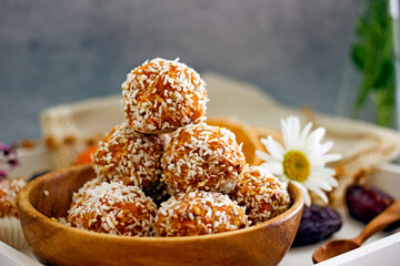 Healthy raw energy balls. Candy vegan balls of dates, coconut pulp, carrots in a wooden bowl are laid out in the shape of a pyramid. Top view, concept of useful home-made candies without sugar