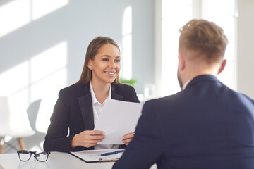 Fototapeta na wymiar Successful interview. Positive girl employer listens to a job seeker sitting at a table in the office.