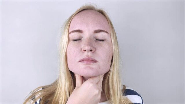 The girl touches the upper part of the neck. Pain is visible on her face. Inflamed lymph nodes due to the common cold, influenza virus, or coronovirus.