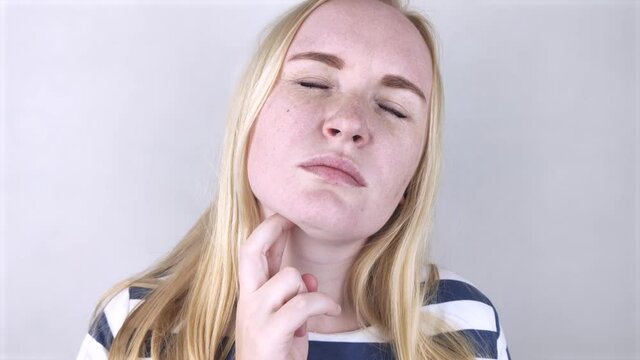The girl touches the upper part of the neck. Pain is visible on her face. Inflamed lymph nodes due to the common cold, influenza virus, or coronovirus.