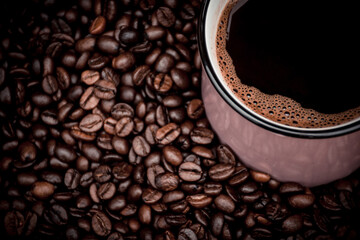 a mug filled with black coffee and beans in the background