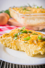 Delicious potato casserole with egg and cheese on a gray wooden background